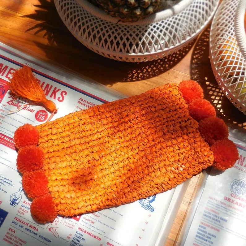 Brunna Canggu Woven Straw Clutch - in Tangerine Orange Raffia & Pom-poms